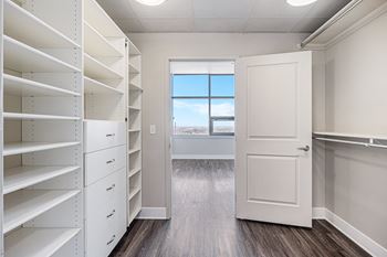 A white closet with shelves and a door leading to a balcony.